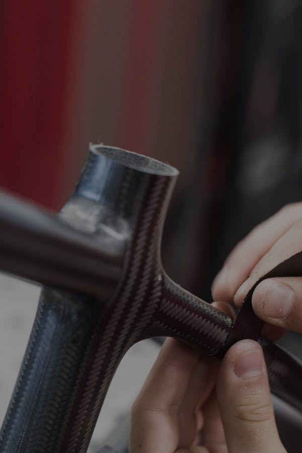 An engineer adding pieces of carbon fiber to the rear triangle of a hardtail bicycle frame