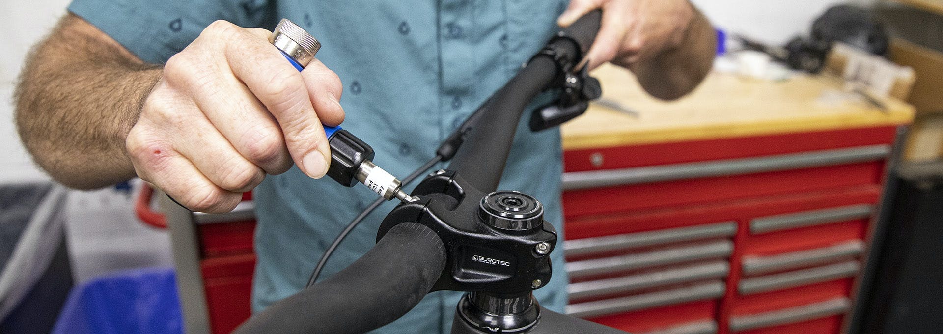 A bicycle mechanic tightening the faceplace bolts on a Burgtec Stem